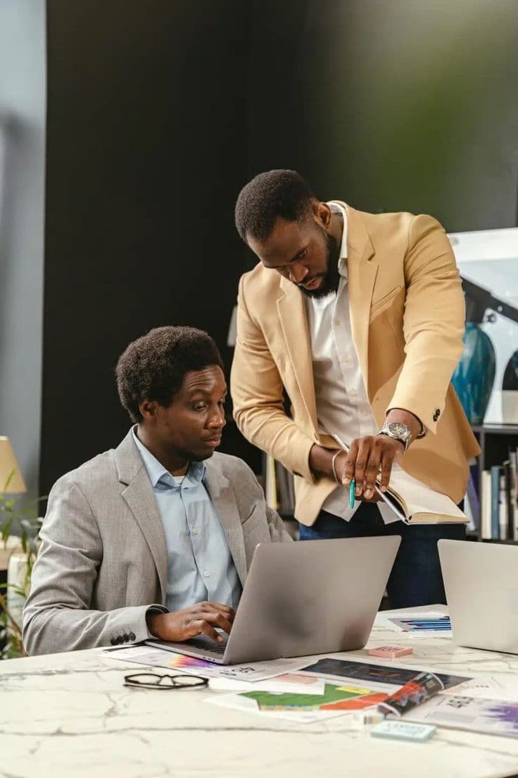Two Nigerian professionals collaborating on a laptop in a modern office